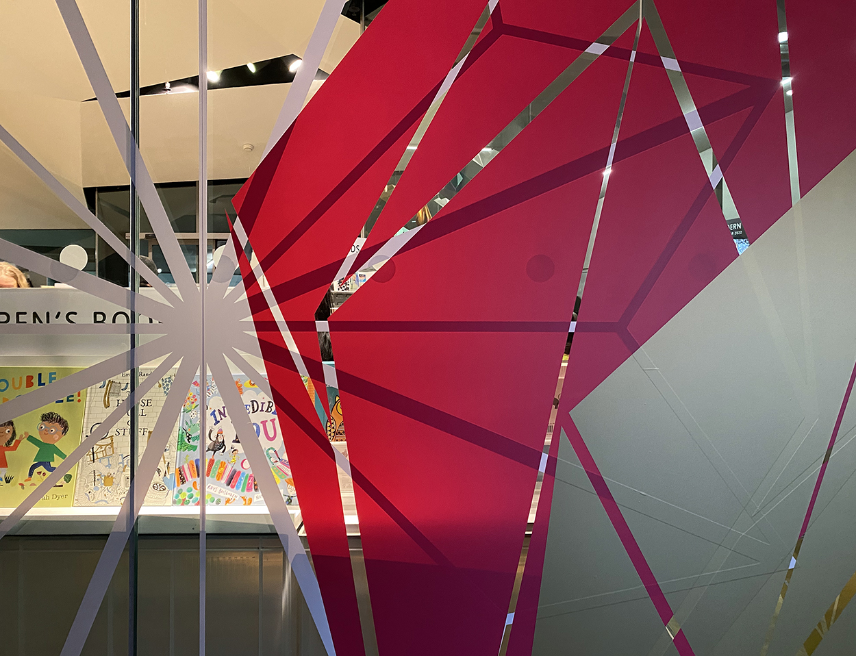 Red and white geometric festive stars placed onto the glass windows of the Tate Modern shop